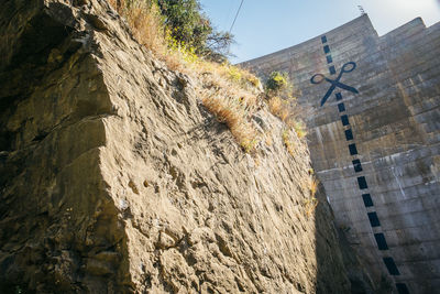 Low angle view of cross on rock against building