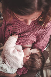 Mother breastfeeding daughter at home