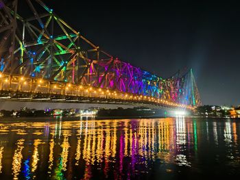 Illuminated bridge over river at night