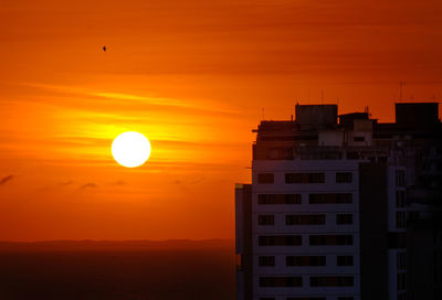 Silhouette buildings against romantic sky at sunset