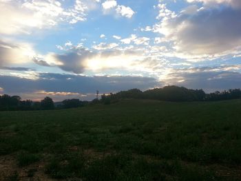 Scenic view of grassy field against cloudy sky