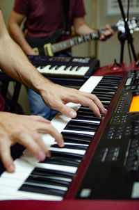 Cropped hands playing piano by man with guitar