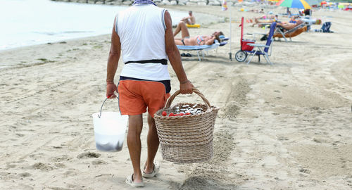 Rear view of man walking on sand