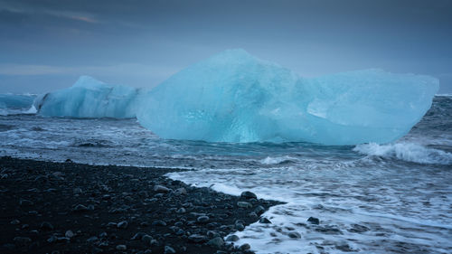 Scenic view of icebergs in sea against sky