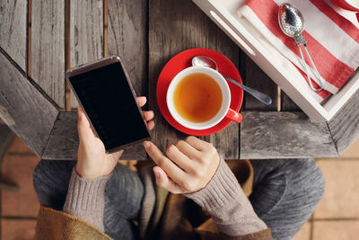 Midsection of woman holding coffee cup on table