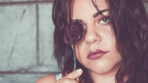 Close-up portrait of woman with wilted rose