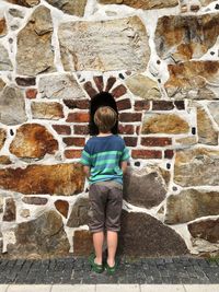 Rear view of woman standing against wall