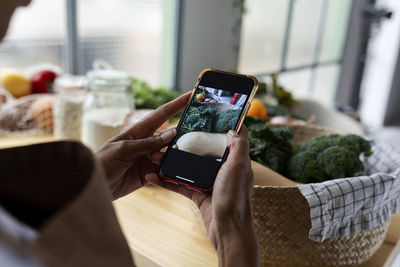 Midsection of person photographing with mobile phone