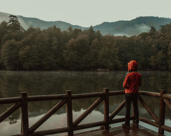 Rear view of woman standing by railing on lake