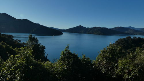 Scenic view of sea and mountains against clear blue sky