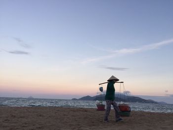 Man on beach against sky during sunset