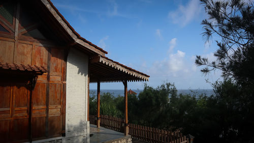 Built structure by trees and building against sky