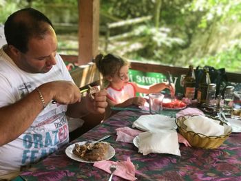 Father and daughter eating food at table in restaurant