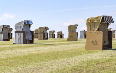 Hooded beach chairs on field against sky