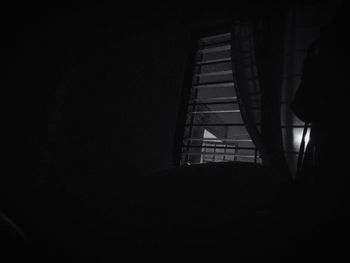 Silhouette man standing by window in dark room