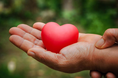 Cropped hand holding heart shape outdoors