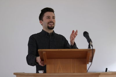 Full length of a smiling young man standing against wall