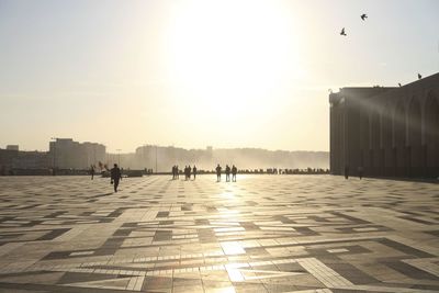 Silhouette people in city against sky during sunset