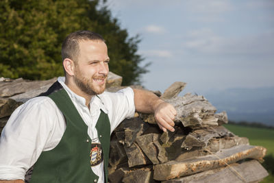 Man in traditional clothing looking away while standing by wood