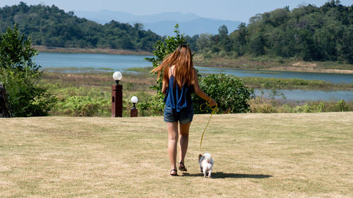 Rear view of a woman walking dog