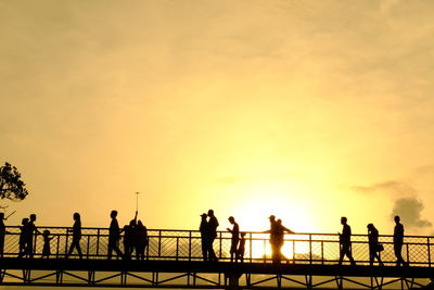 Silhouette people by sea against sky during sunset