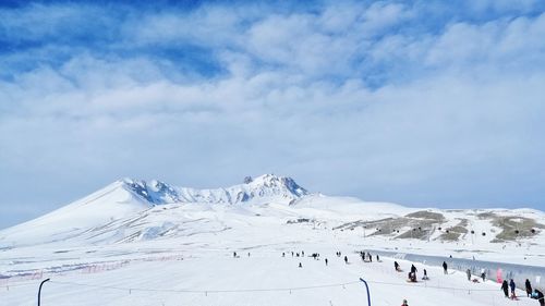 Group of people on snowcapped mountain against sky