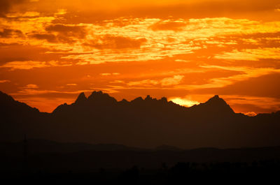 Scenic view of silhouette mountains against orange sky