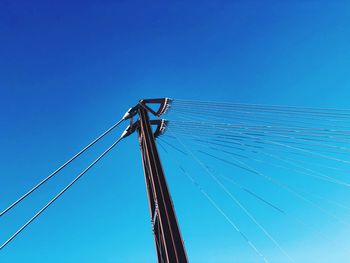 Low angle view of power lines against clear blue sky 