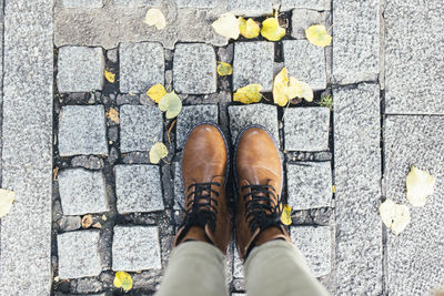 Selfie image of brown lace up boots on a stone floor with yellow autumn leaves