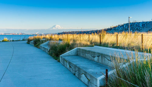 Footpath by river against clear blue sky