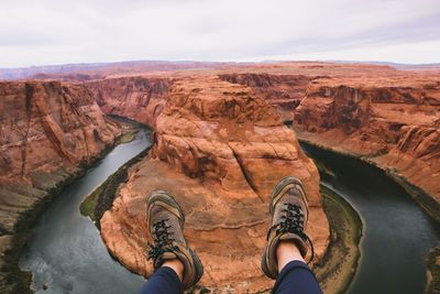 Low section of man on rock against sky