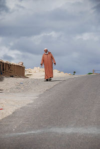 Rear view of man walking on land against sky