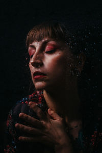 Close-up portrait of a young woman over black background