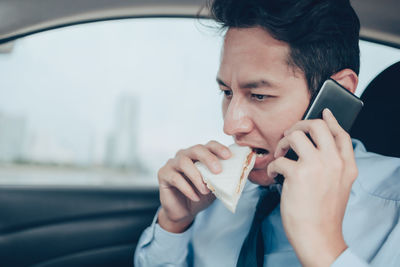 Portrait of man using mobile phone in car