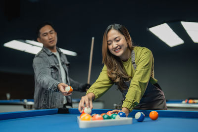 Portrait of young woman playing pool table