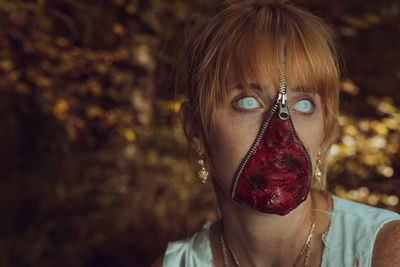 Woman with zipper and face paint against tree