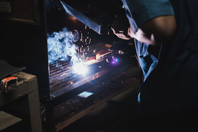 Midsection of man welding metal at factory