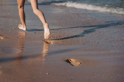 Low section of woman walking at beach