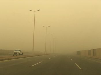 Vehicles on road against sky during foggy weather