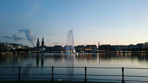 Alster lake by city against sky at dusk