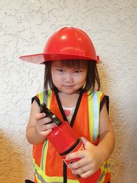 Portrait of woman holding red while standing against wall