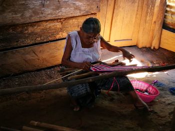 High angle view of senior woman weaving on handloom