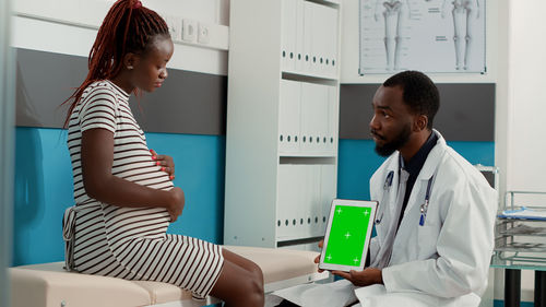 Doctor showing digital tablet to patient in clinic