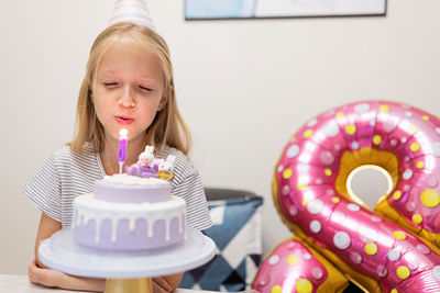 Cheerful girl sitting by balloon during birthday