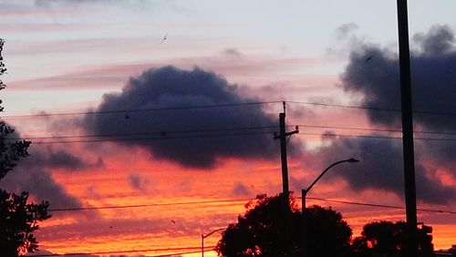 Low angle view of silhouette trees against cloudy sky