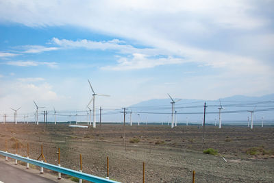 Wind turbines on field against sky