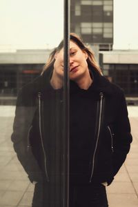 Portrait of young woman standing against wall