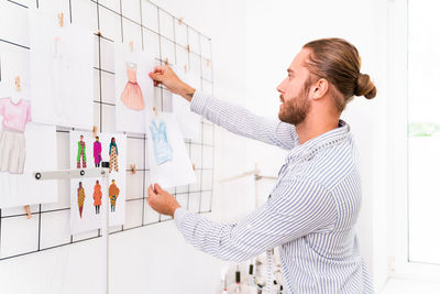 Side view of fashion designer holding drawing at studio