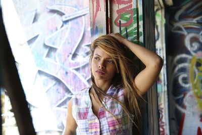 Portrait of teenage girl standing against graffiti