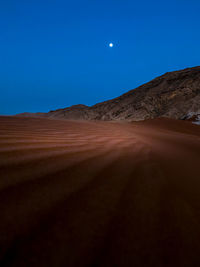 Scenic view of desert against clear blue sky